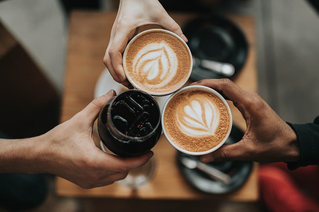 Tres personas juntan sus bebidas sobre una mesa